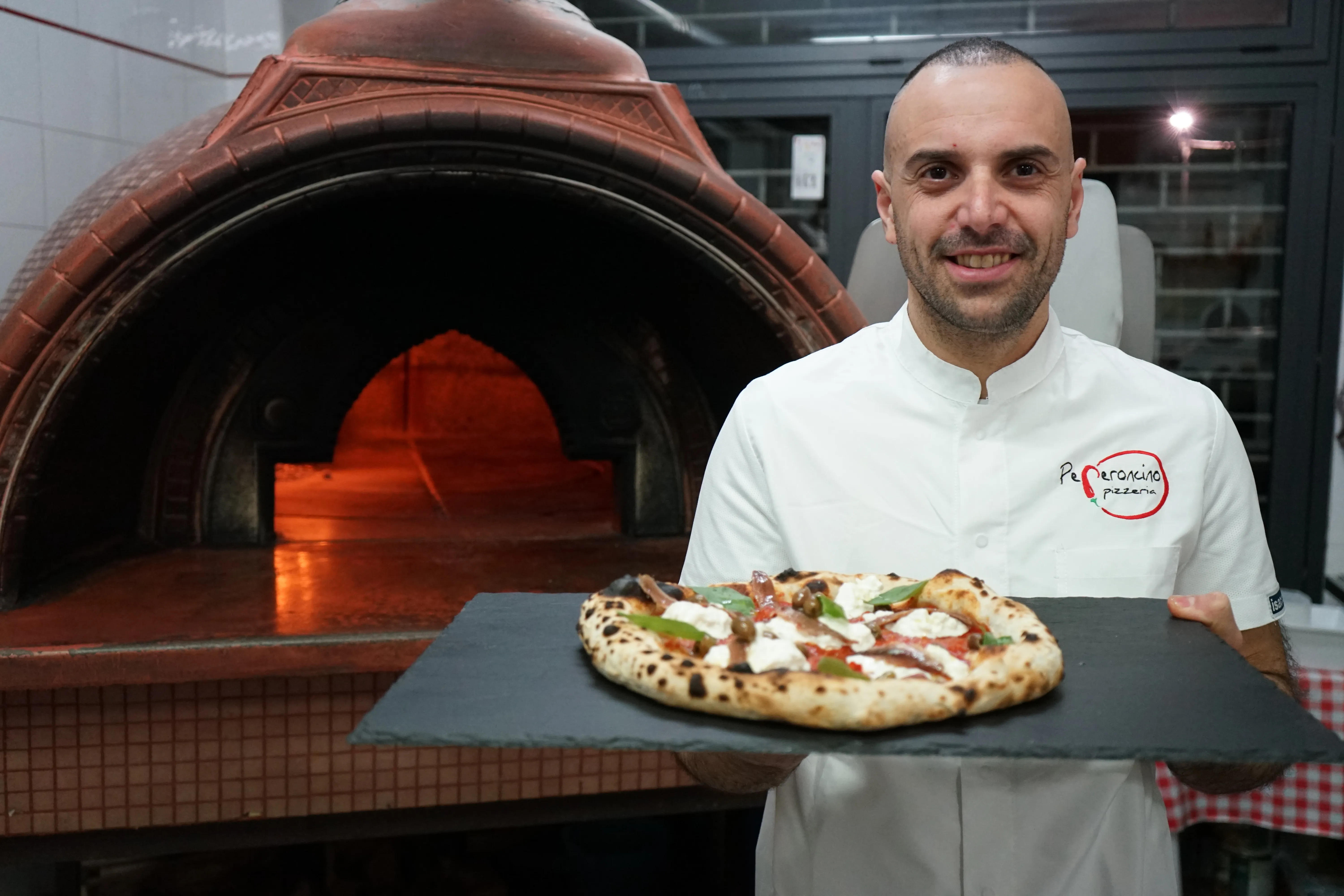Giuseppe Carpino davanti al forno con una pizza appena sfornata